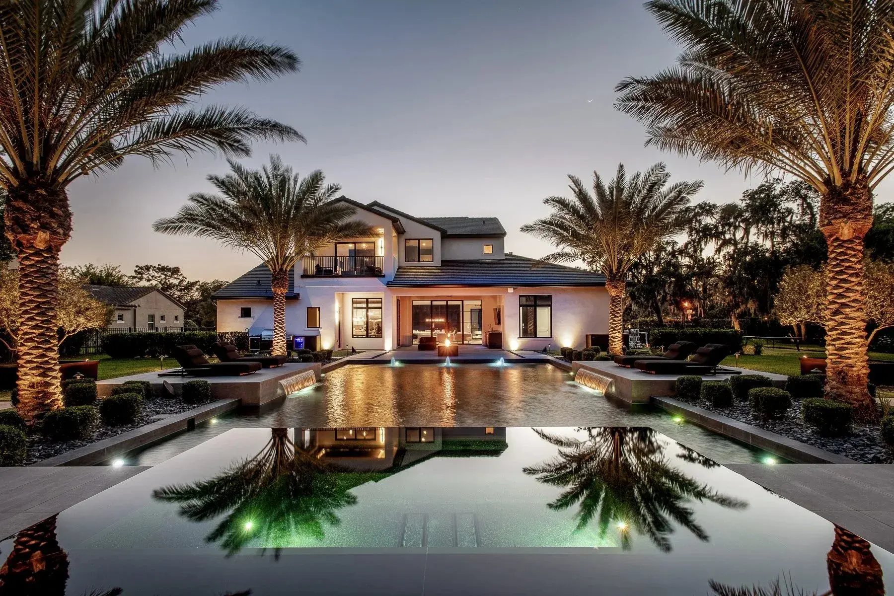 Luxury Florida estate at dusk mirrored in a lit infinity pool